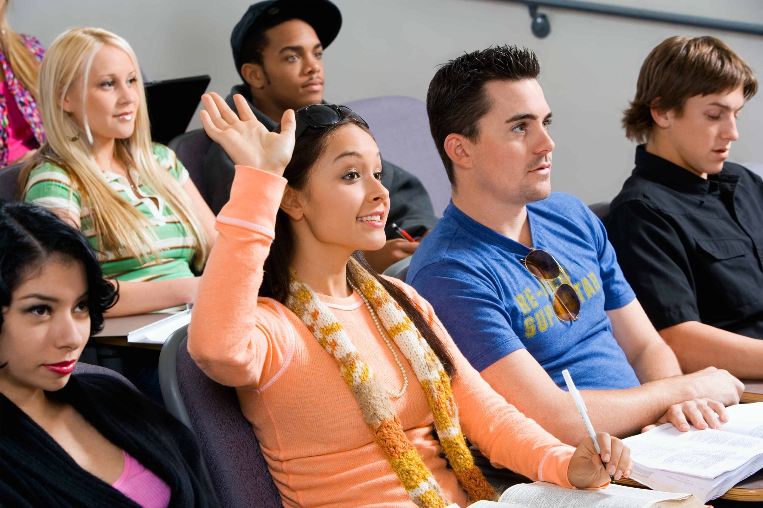 students in financial literacy class, girl in orange shirt raising hand