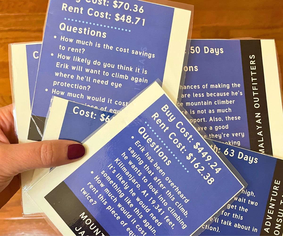 woman holding laminated money hint cards with questions to help students through the different decision-making points