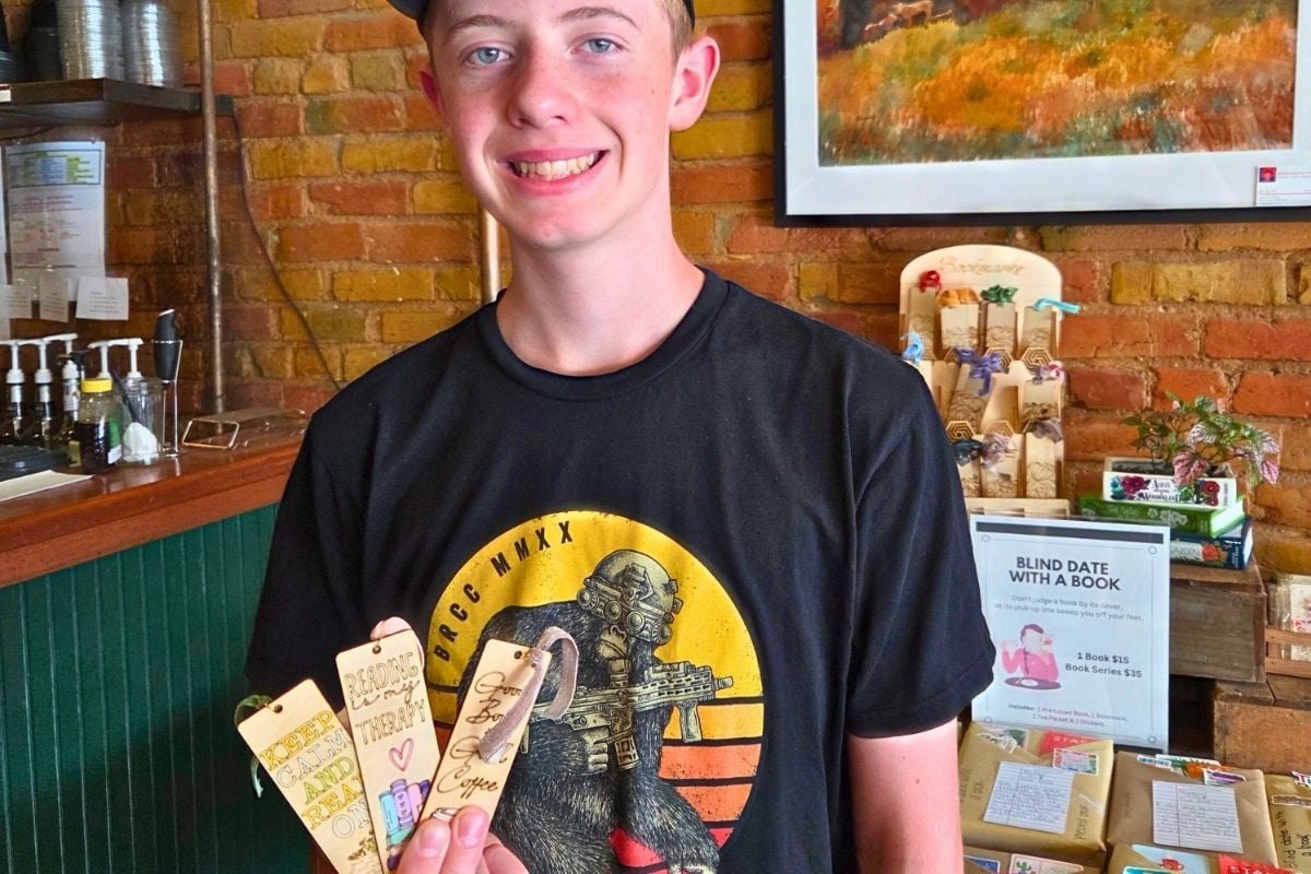 teen boy with handmade CO2 laser bookmarks at a shop